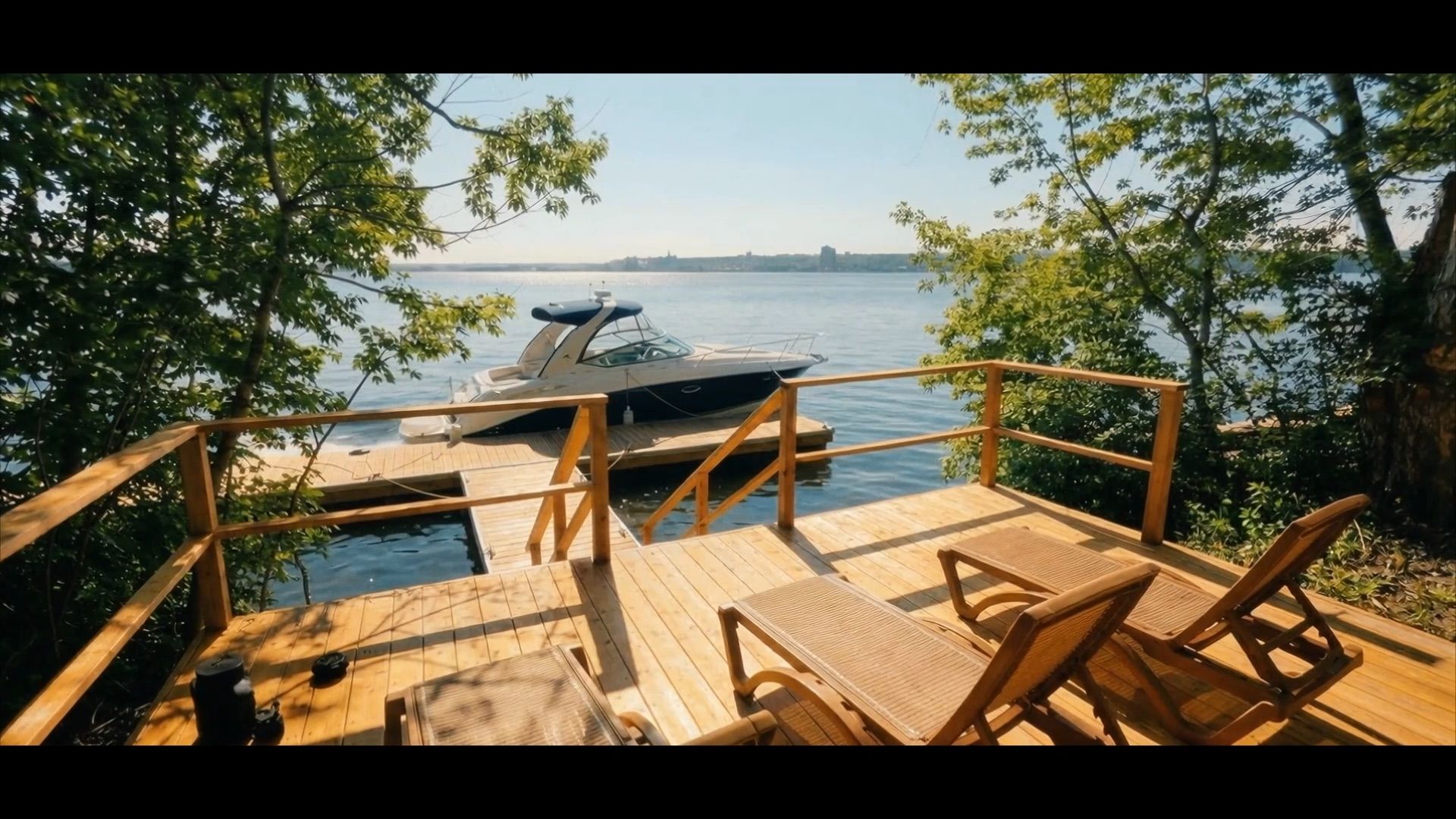 Lounge chairs on a deck at the water on a summer evening (still from the property film)