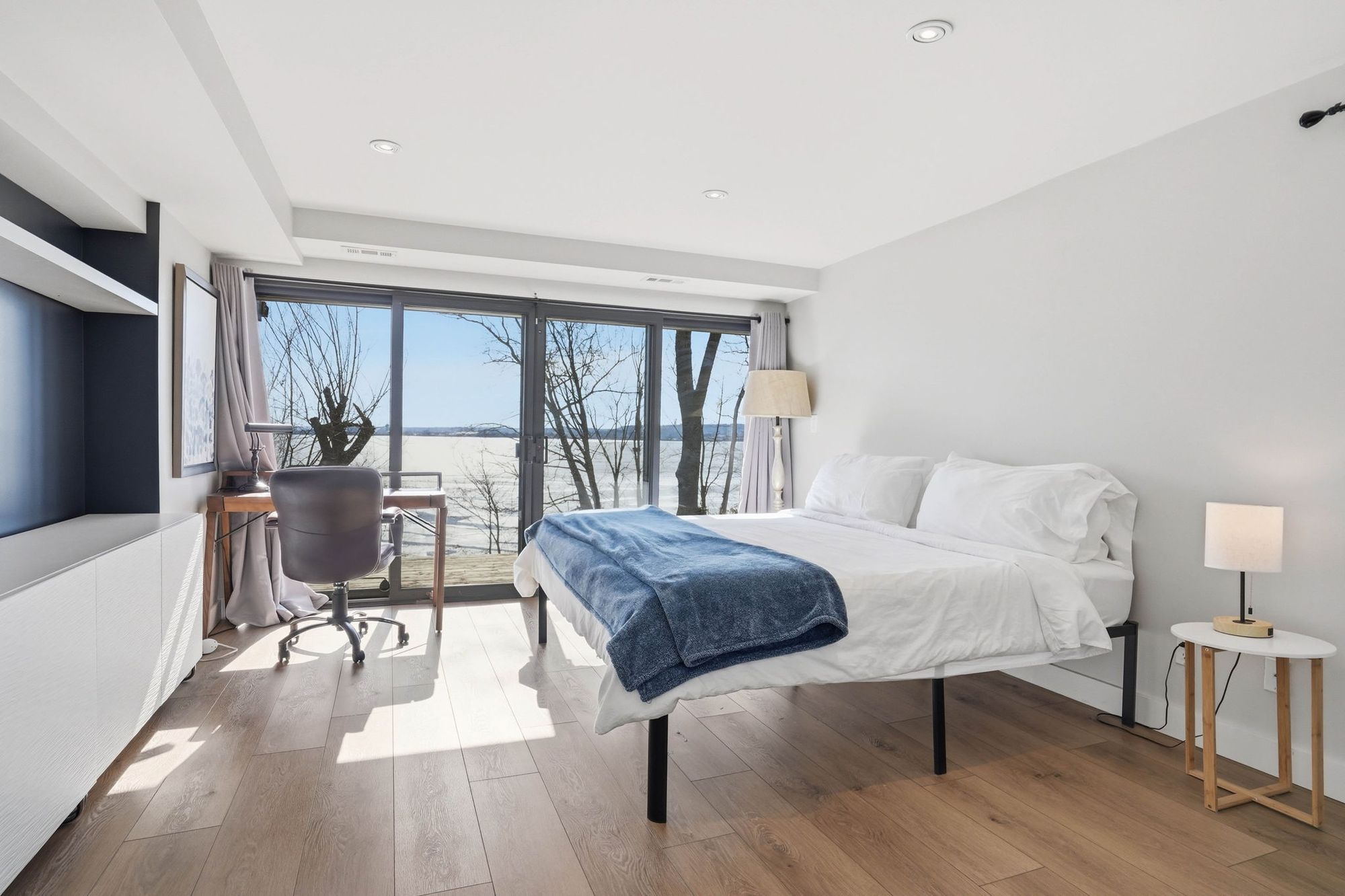 A bedroom with sliding doors to the deck and the bay beyond