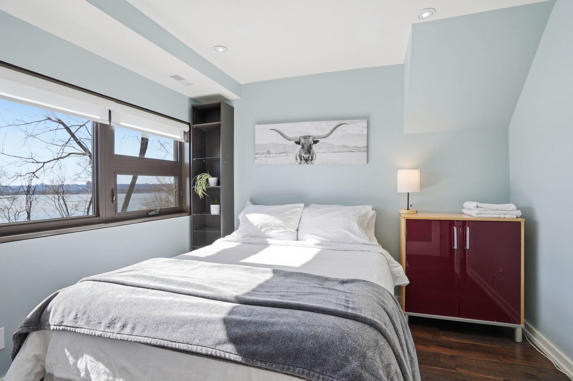 A bedroom with a long window over the treetops