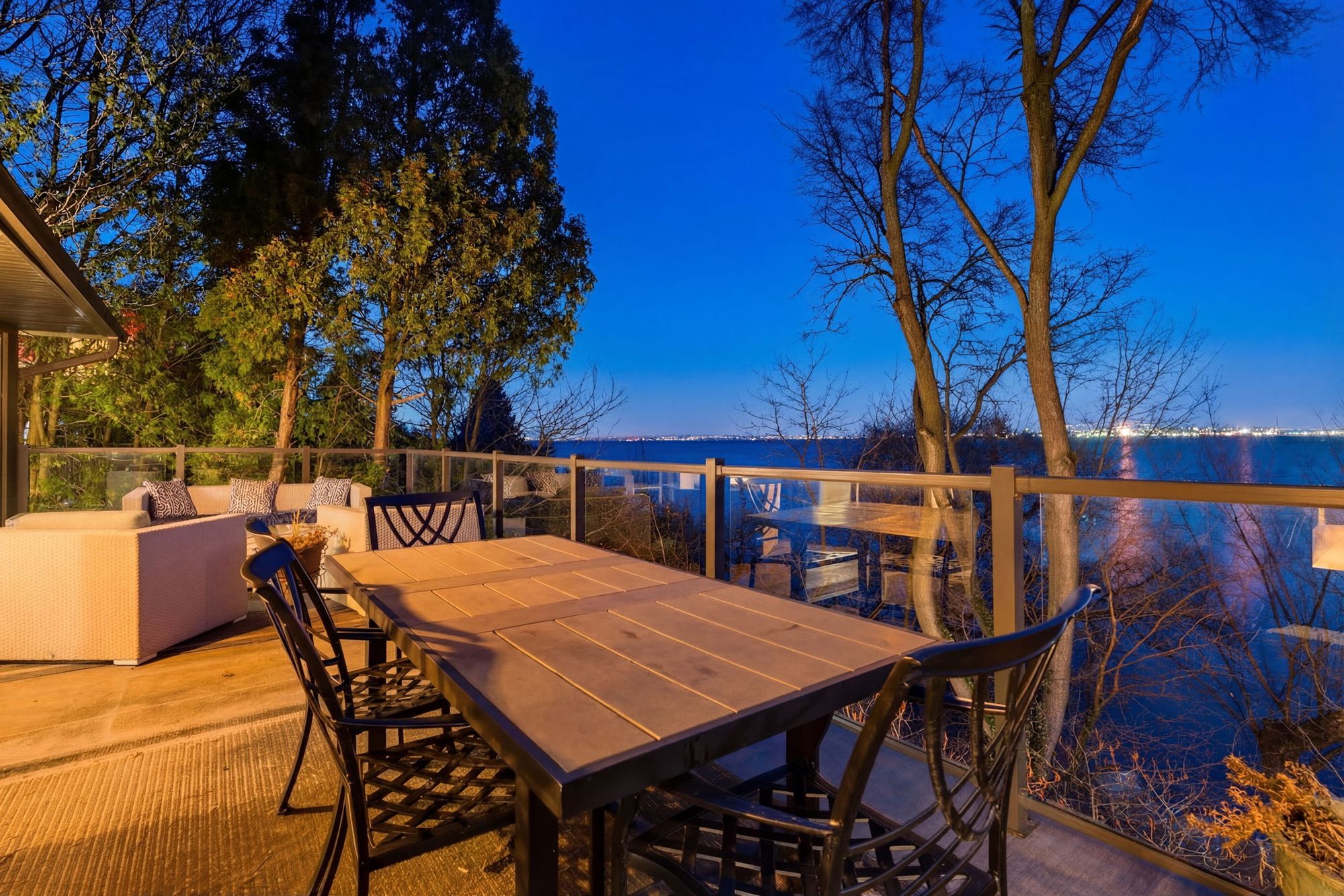 Outdoor dining on the deck at dusk with the bay beyond