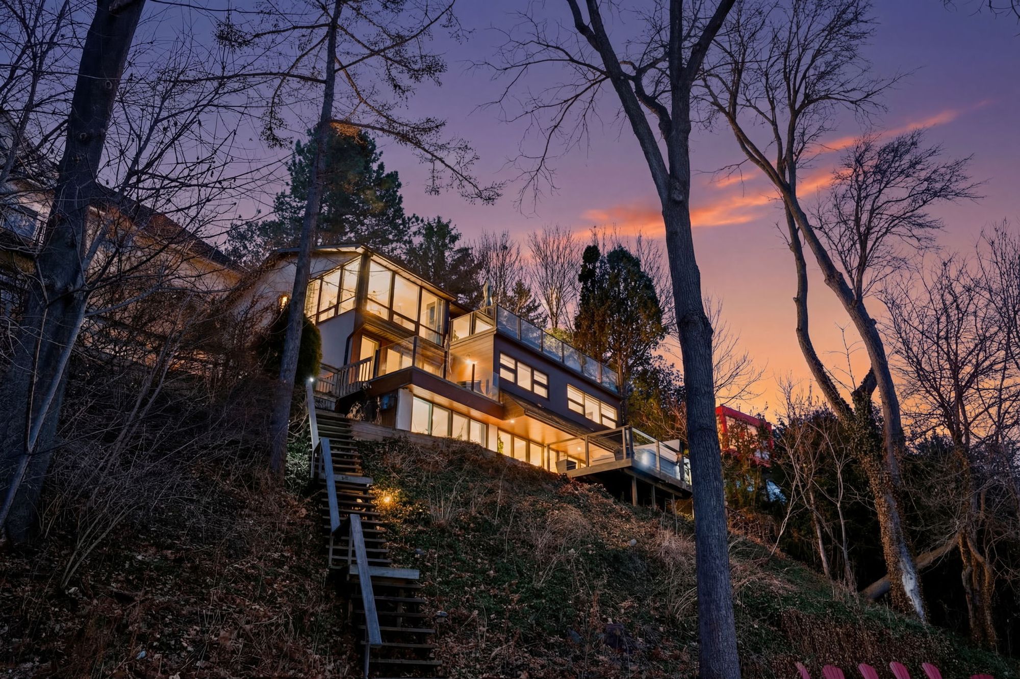 The house lit up on the hill under a sunset sky