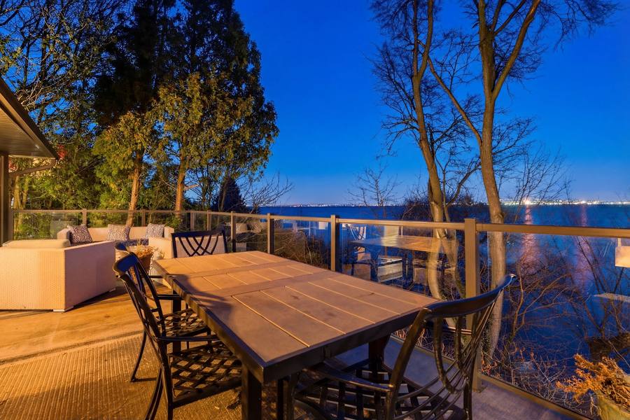 Outdoor dining on the deck at dusk with the bay beyond