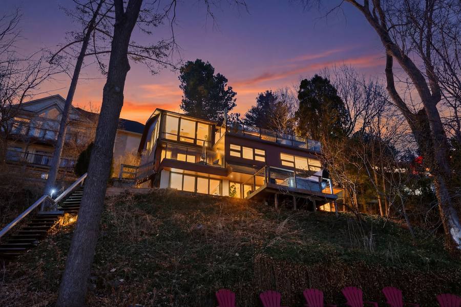 The house glowing on the hill above the bay at dusk